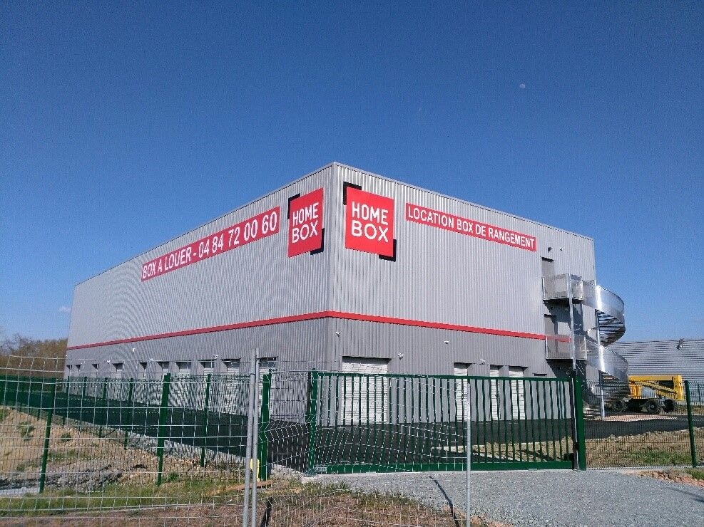 Grey self-storage building with red HOMEBOX signage under blue sky at HOMEBOX Vichy, Rue des Morlattes ZAC des Ancises 2, Creuzier-le-Neuf