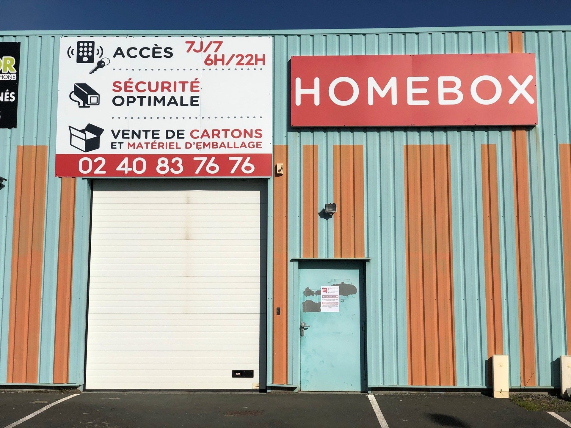 Turquoise and orange striped metal facade with white loading door at HOMEBOX Ancenis, 225 boulevard de la Prairie, Saint Gereon