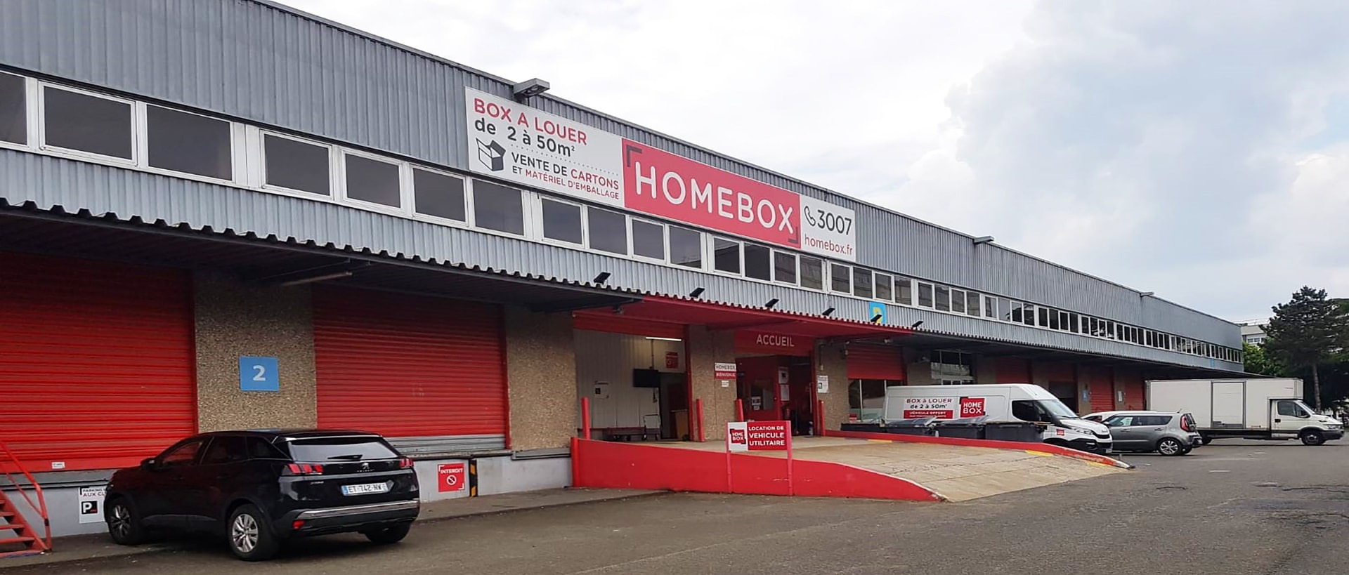Grey warehouse facade with HOMEBOX sign, Box à Louer banner and red entrance ramp at HOMEBOX Nanterre - La Défense, 73 rue Noël Pons, Nanterre