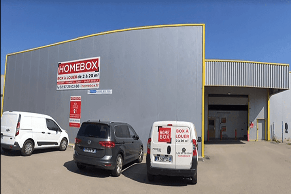 Façade grise avec enseigne et véhicules utilitaires devant l'entrée, HOMEBOX Lorient, ZI de Kerloic à Caudan