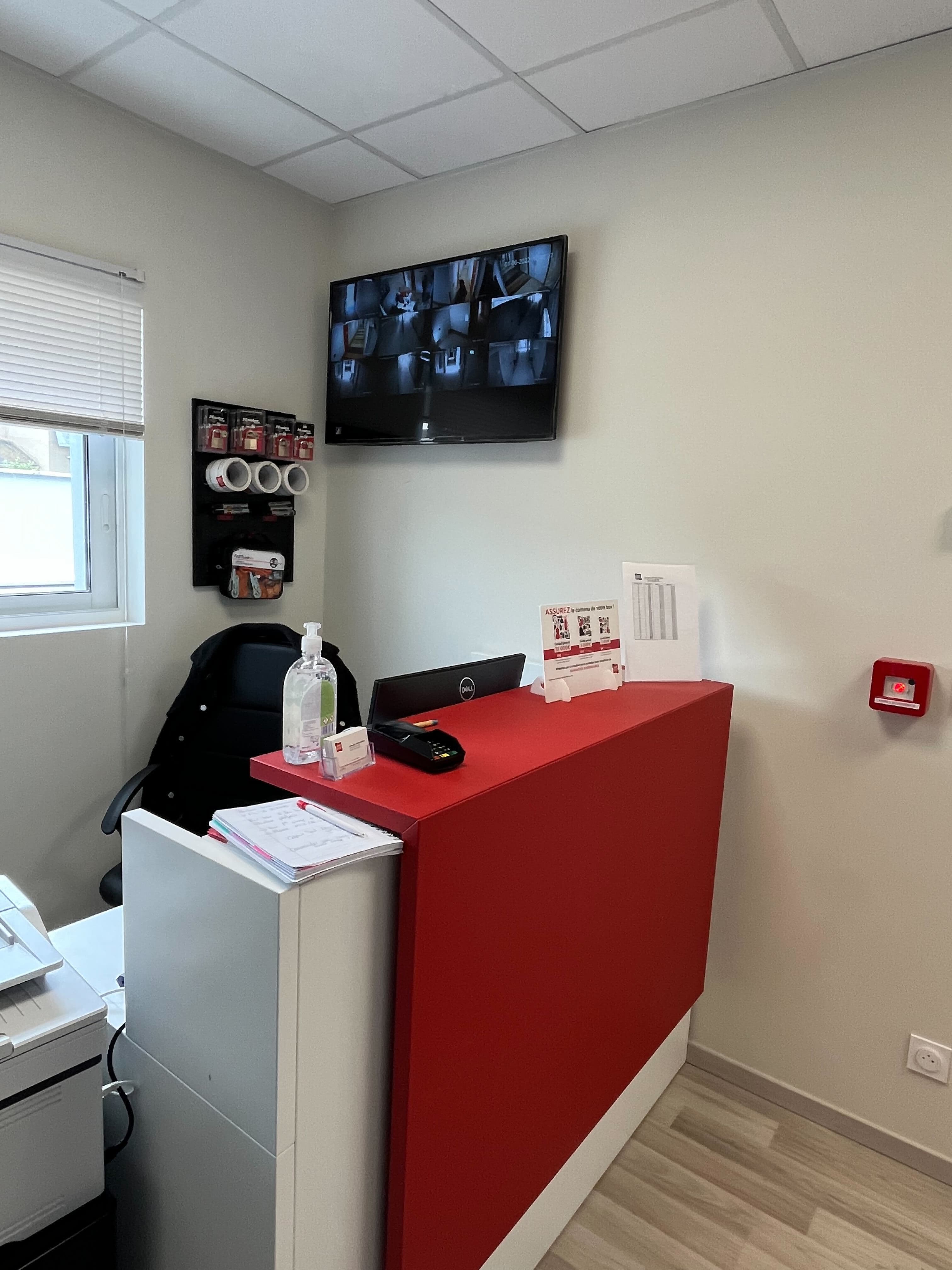 Accueil avec comptoir rouge et écrans de vidéosurveillance au centre HOMEBOX Châteauroux.