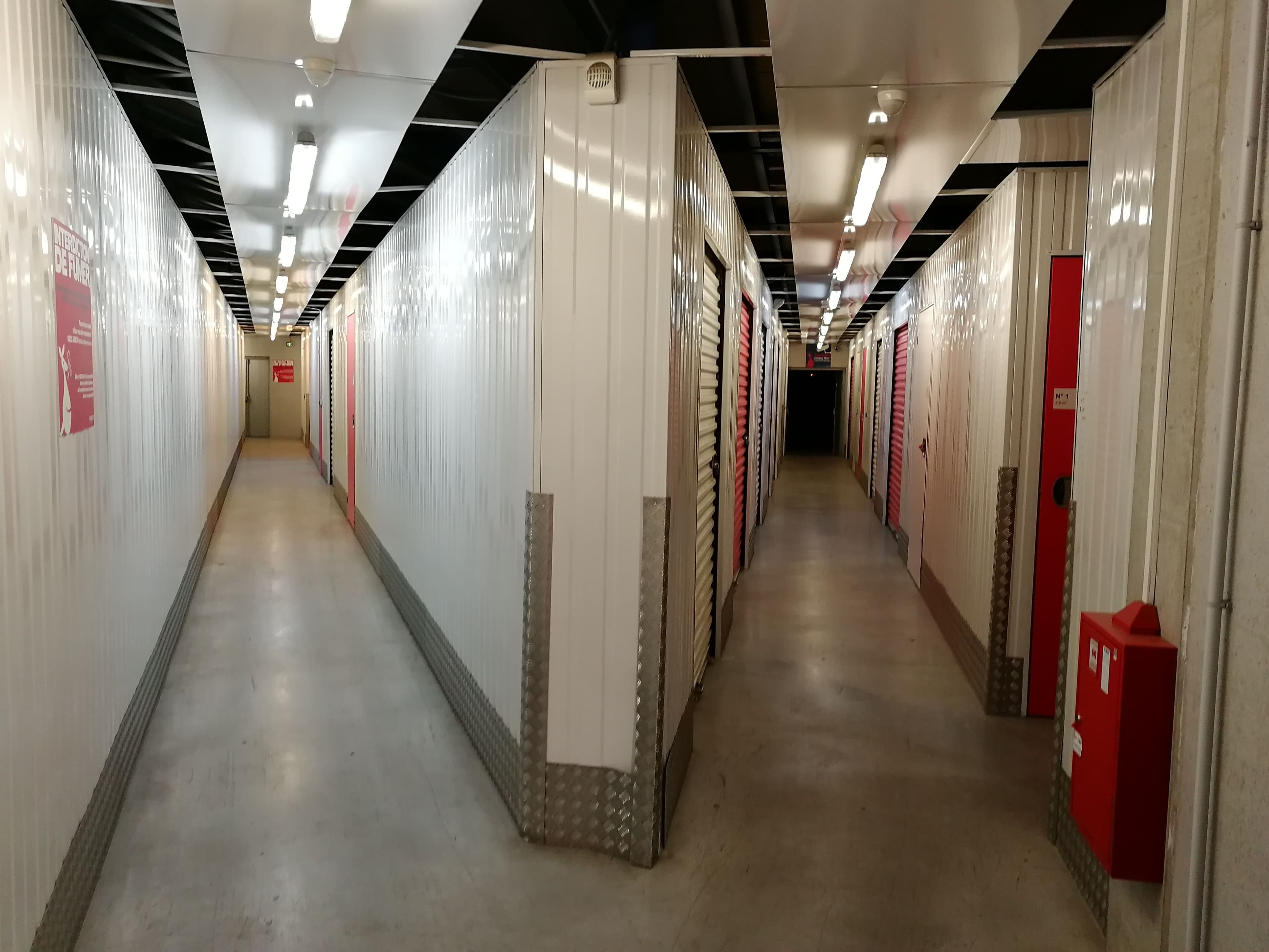 Couloirs intérieurs du centre HOMEBOX Auray avec portes de box blanches et rouges.