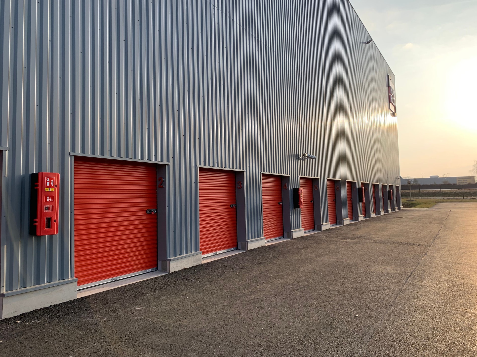 Alignement de box extérieurs du centre HOMEBOX Amiens - Glisy avec portes roulantes rouges.