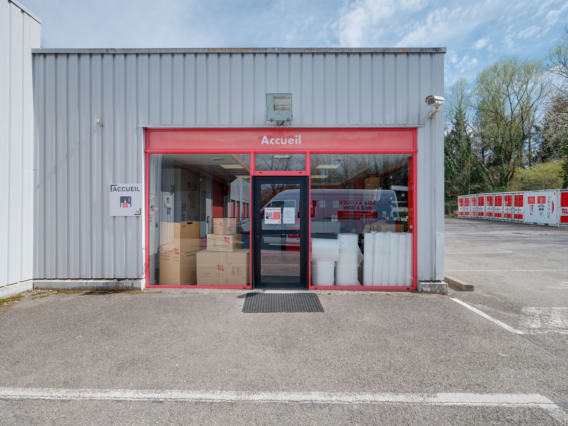 Small grey and red reception building with packing boxes visible through window at HOMEBOX Annecy (Cran-Gevrier), 1 route de la salle Cran gevrier ZAC des romains sud, Annecy