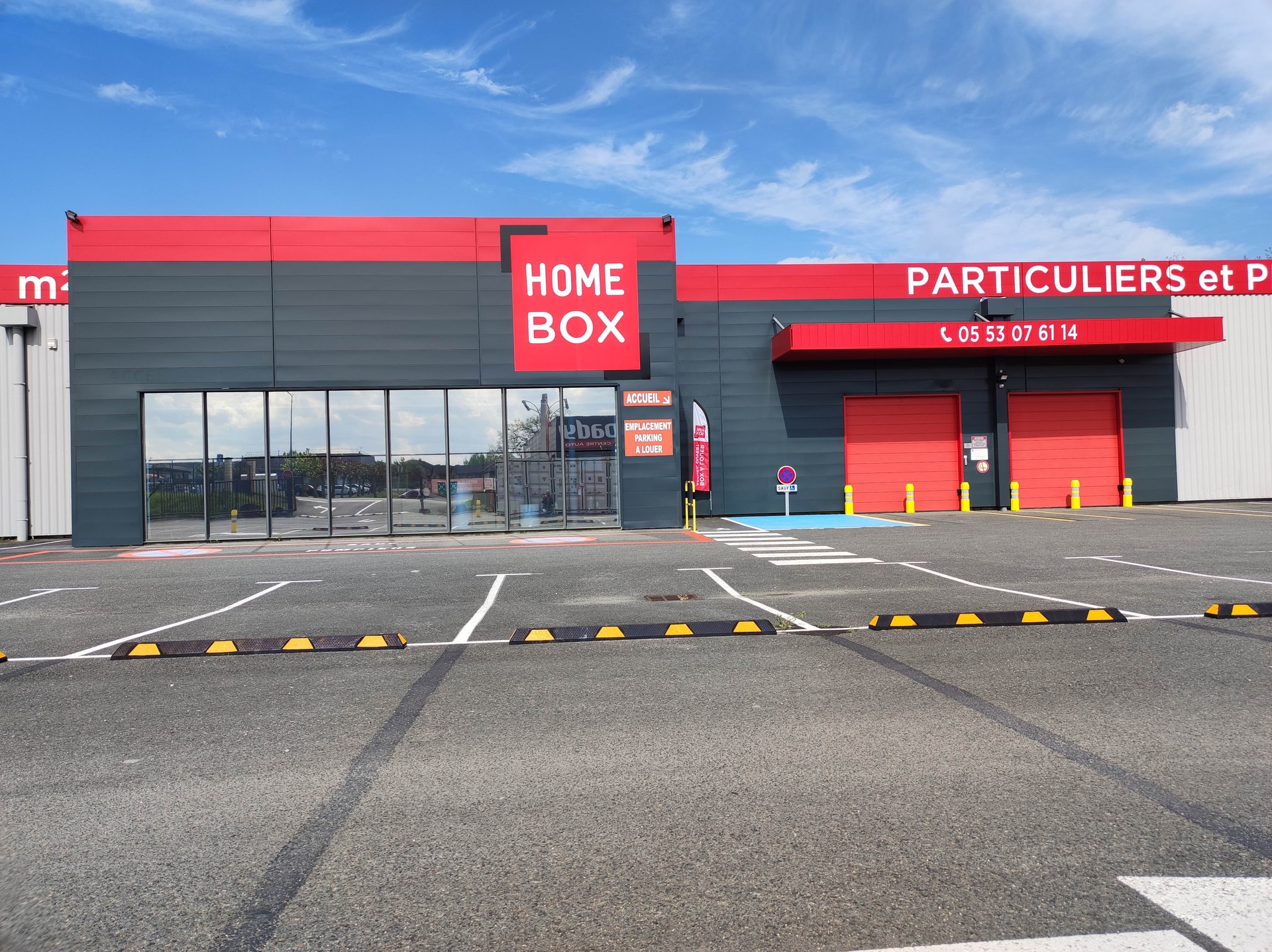 Modern grey and red storage facility facade with parking spaces at HOMEBOX Périgueux, Rue des digitales, Trélissac