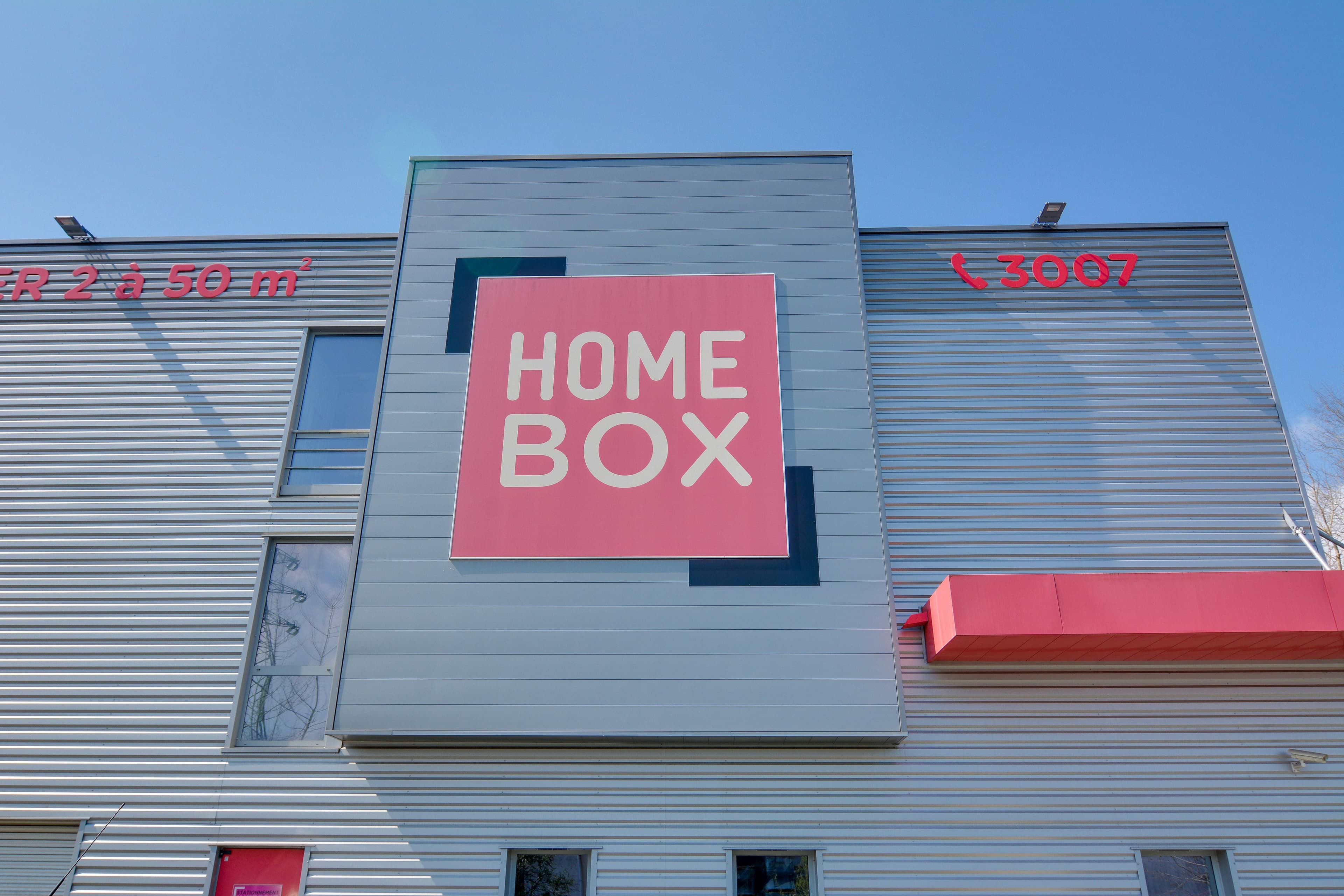 Logo HOMEBOX sur la façade du centre HOMEBOX Angers, bâtiment gris avec encadrement rouge et noir.