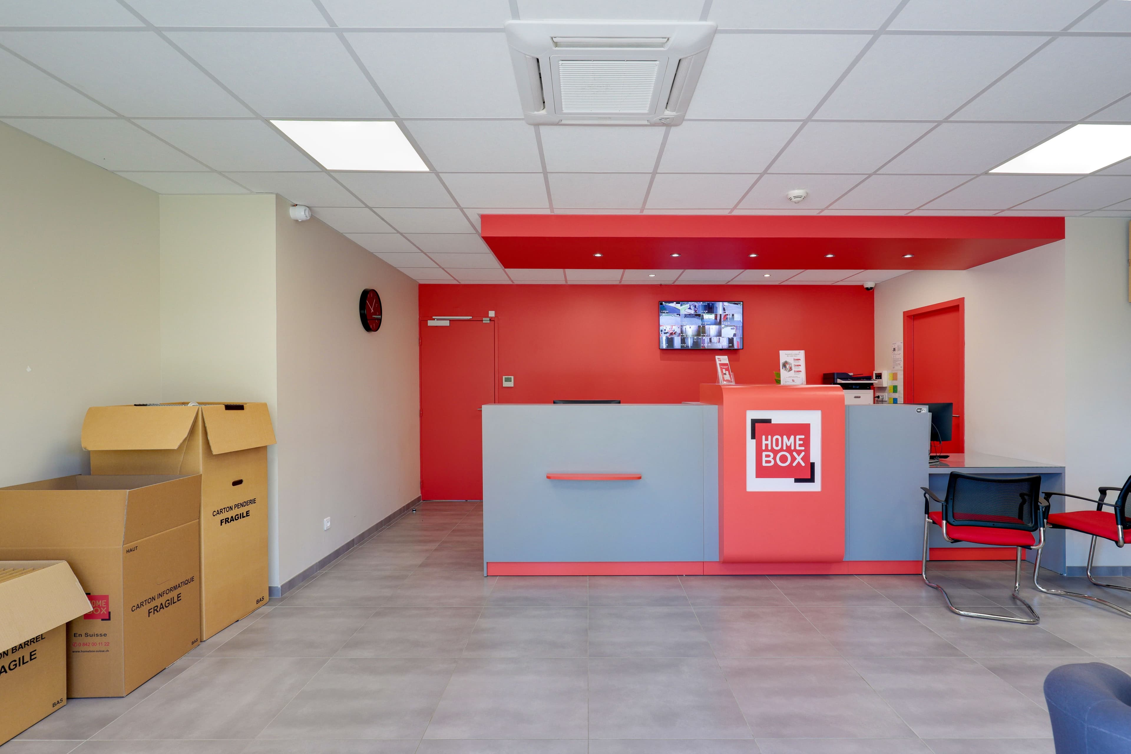 Accueil du centre HOMEBOX Brest avec comptoir rouge et gris.
