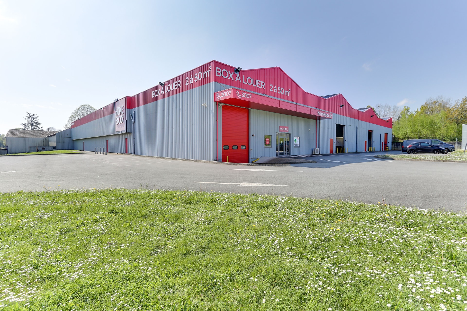 Façade d'angle bardage gris et bandeau rouge Box à louer sous ciel dégagé, HOMEBOX Laval, 19 boulevard du 8 mai 1945 à Laval