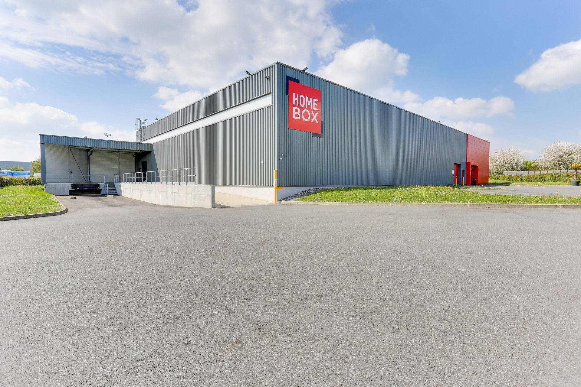 Façade grise avec enseigne rouge HOMEBOX et quai de chargement, HOMEBOX Rennes - Le Rheu, 4 rue des Orchidées à Le Rheu