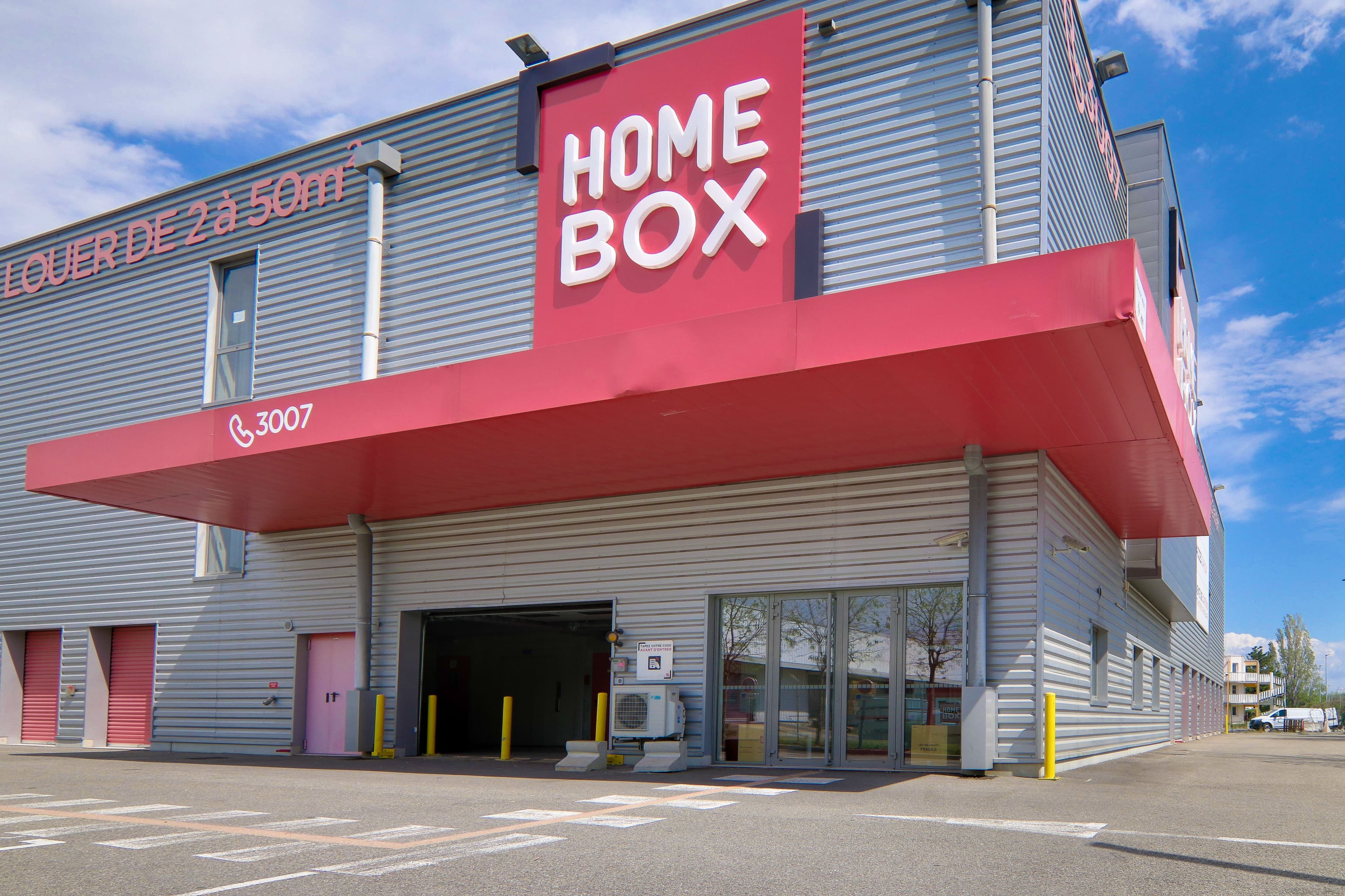 Entrée couverte du centre HOMEBOX Avignon avec large avancée rouge et accès aux box.