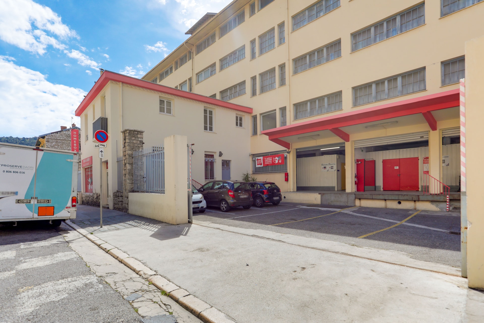 Façade beige avec auvent rouge, parking et accès véhicules, HOMEBOX Nice, 6 rue Leotardi à Nice