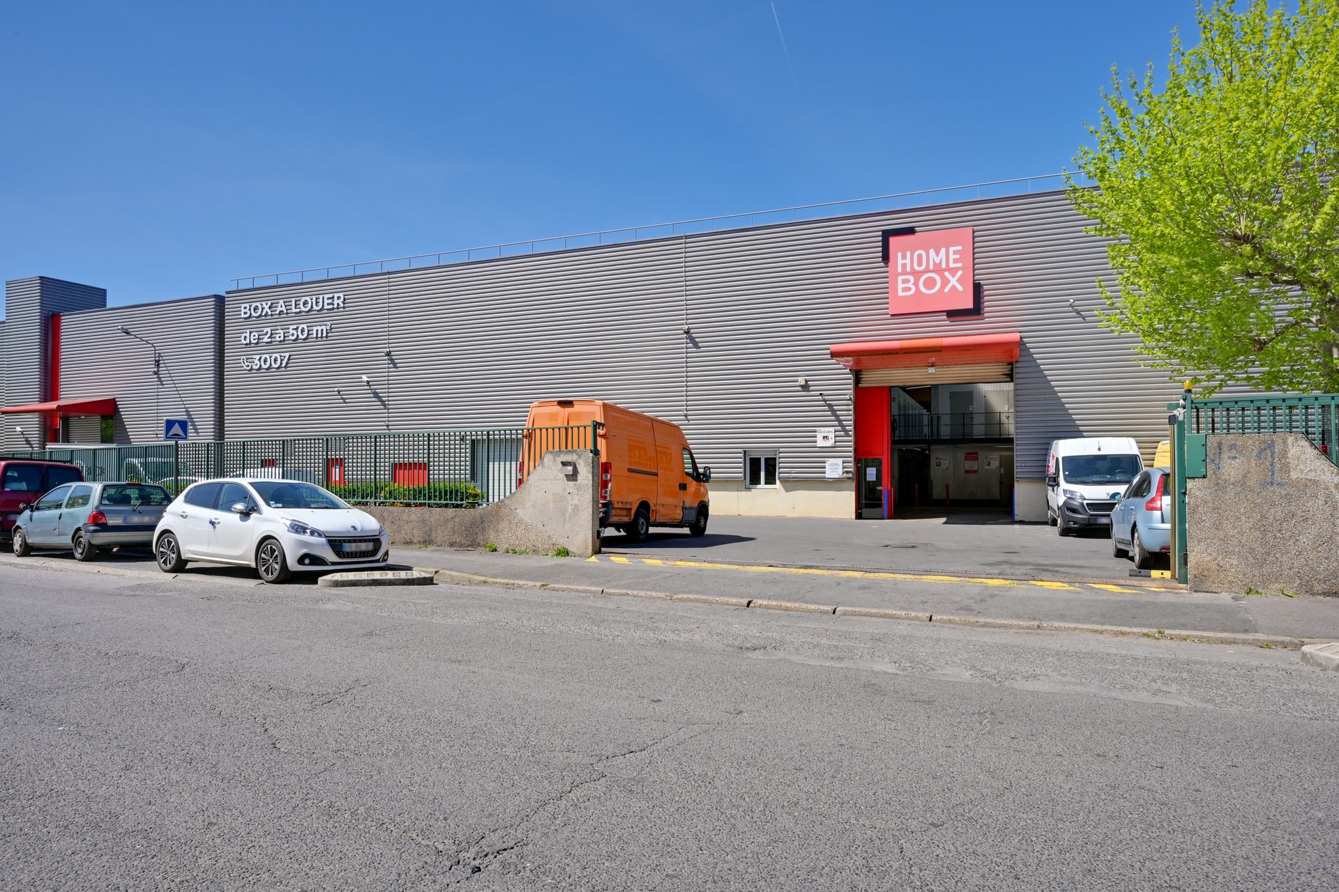 Façade du centre HOMEBOX Bagnolet, rue Jean Lolive, avec parking et véhicules stationnés.