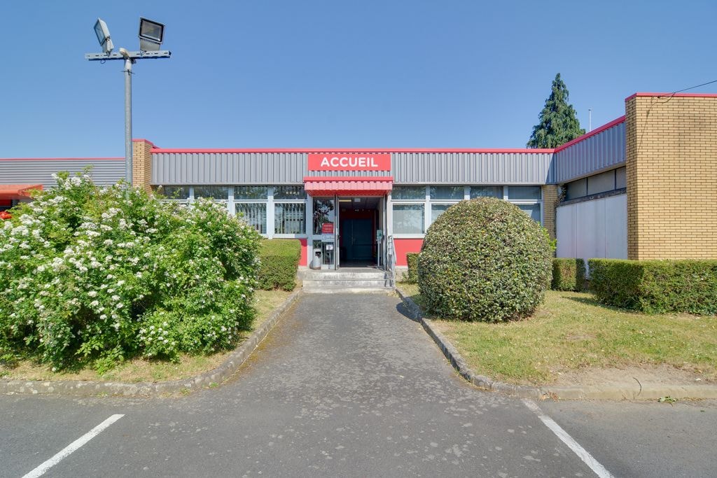 Entrée accueil rouge entourée de haies et d'arbustes fleuris devant le bâtiment, HOMEBOX Nantes, 2 rue du Danemark à Carquefou