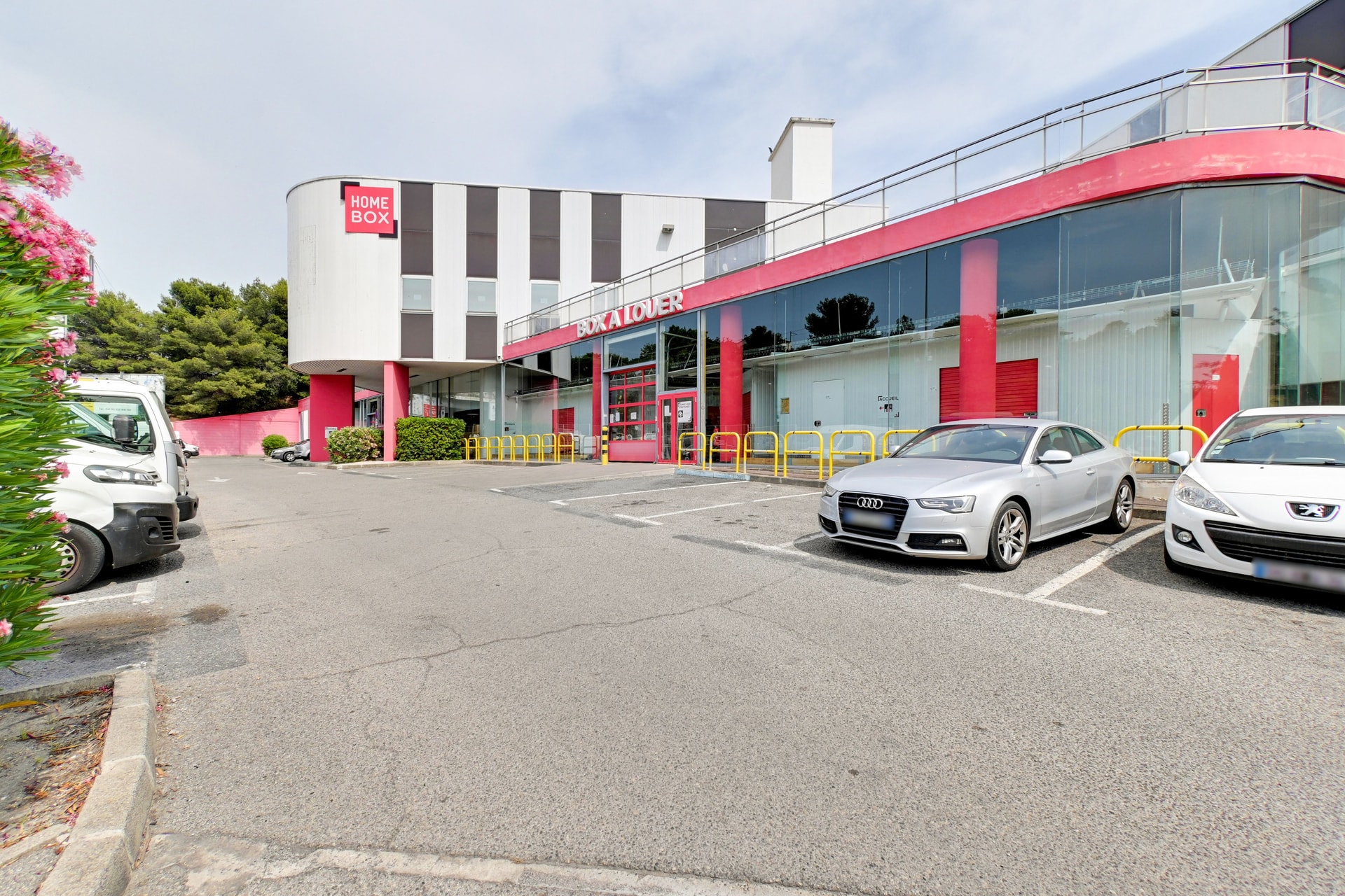 Bâtiment blanc et rouge avec tour d'angle, parking et véhicules, HOMEBOX Marseille - Plombières, 43 Boulevard Guigou à Marseille