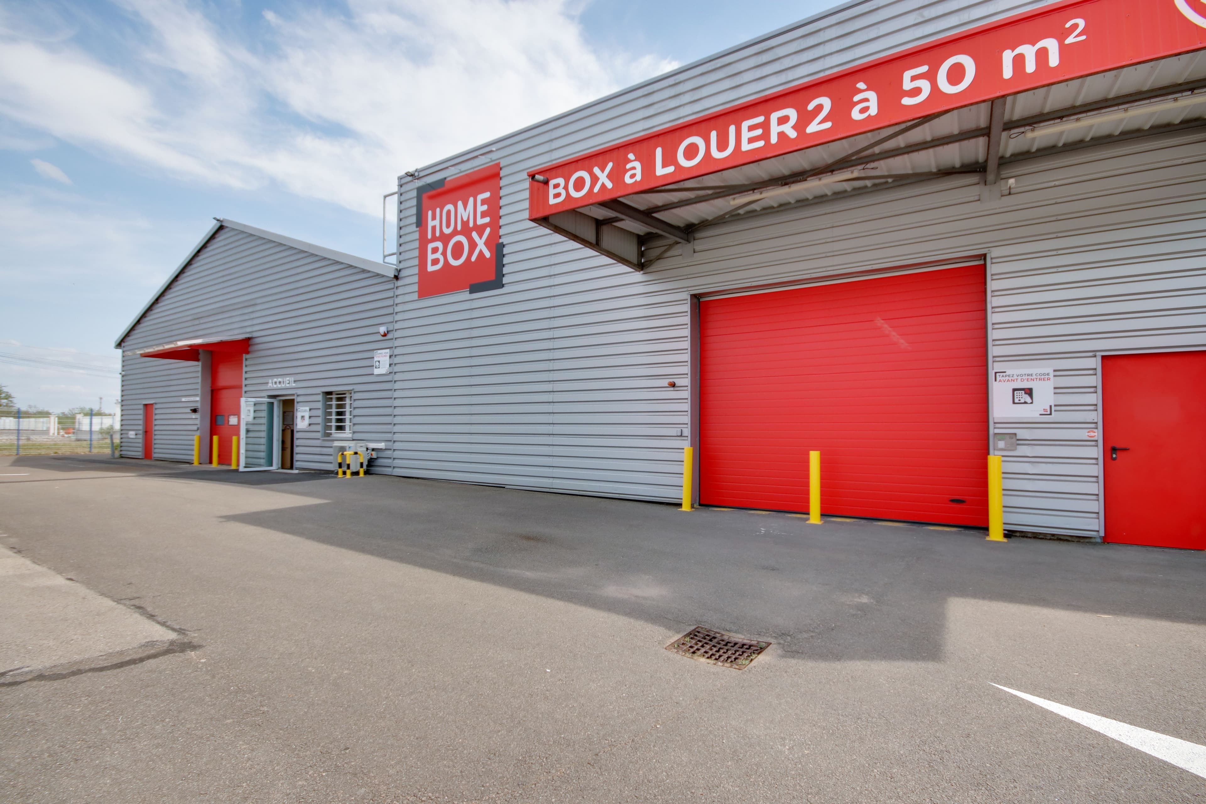 Façade du centre HOMEBOX Dijon avec enseigne rouge et porte roulante.