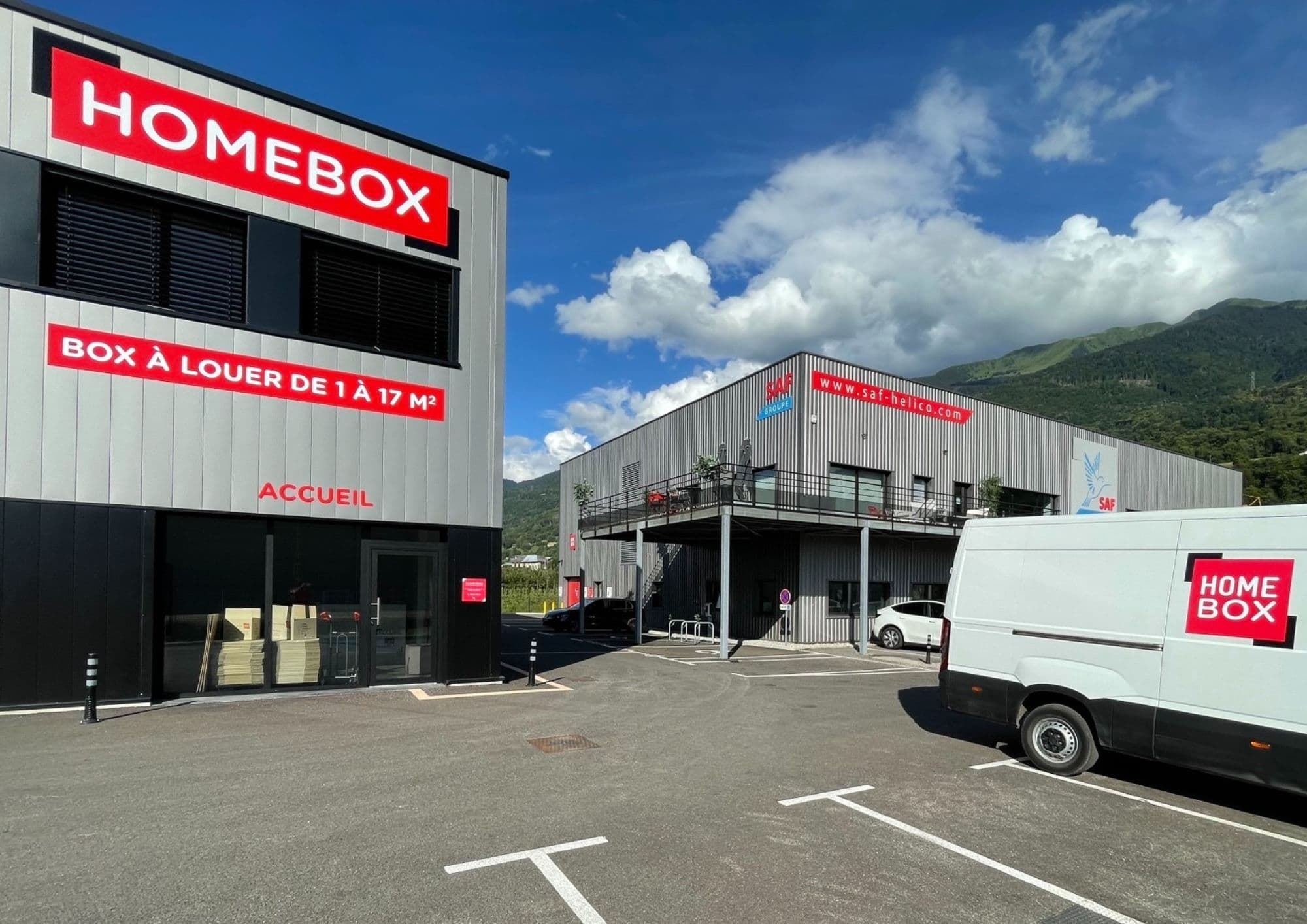 Bâtiments et parking du centre HOMEBOX Albertville avec camionnette stationnée.