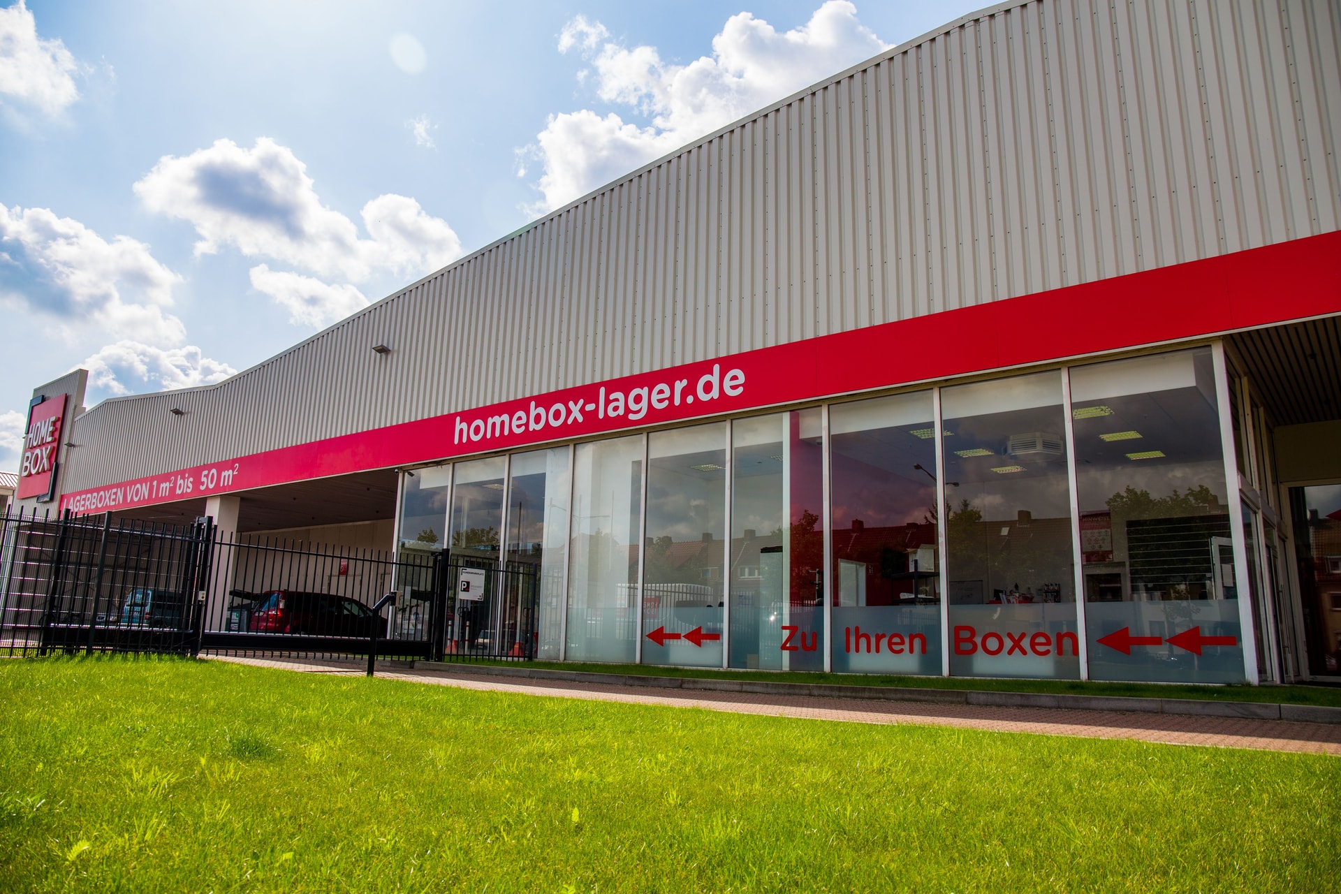 Glazed facade with red HOMEBOX signage and grassy front at HOMEBOX Bremen, Pfalzburger Strasse 71, Bremen