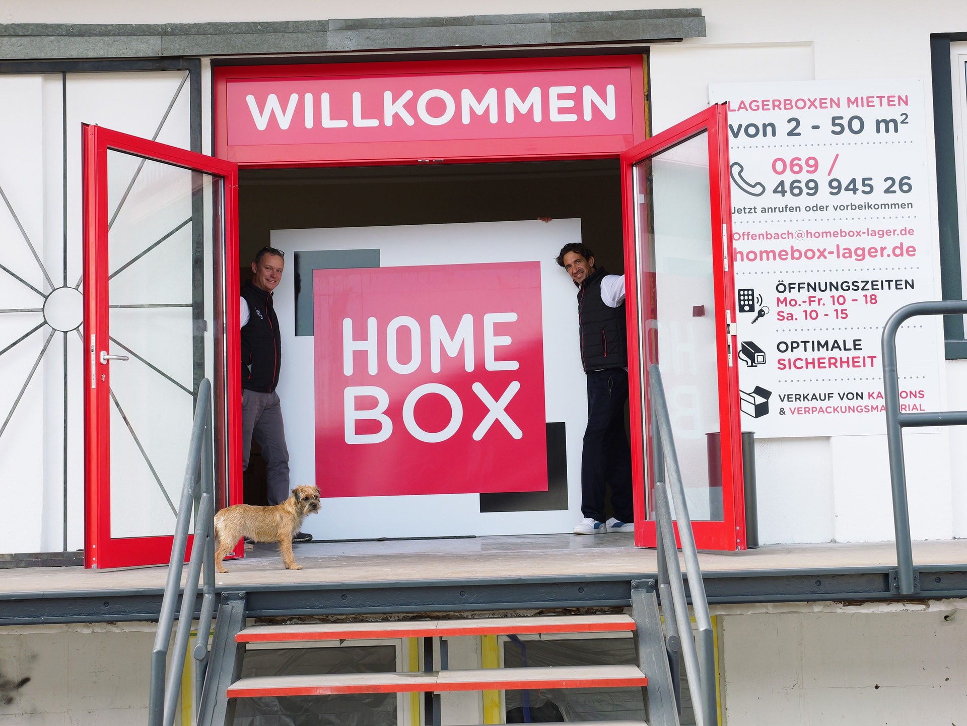 Welcoming entrance with Willkommen sign, staff and dog by large HOMEBOX logo at HOMEBOX Offenbach, Mühlheimer Straße 183-185, Offenbach