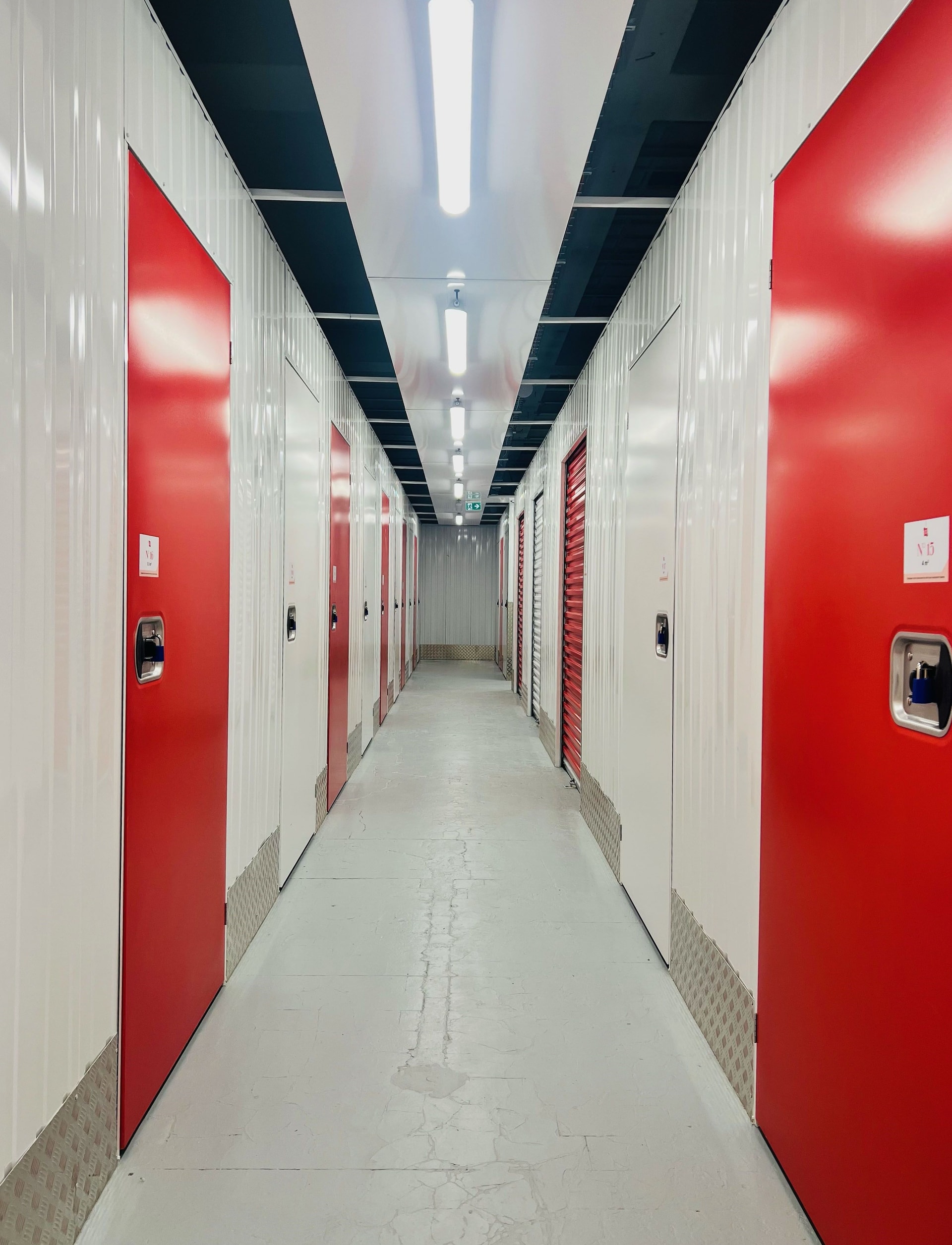 Long couloir intérieur bordé de boxes individuels aux portes rouges du centre HOMEBOX Paris République