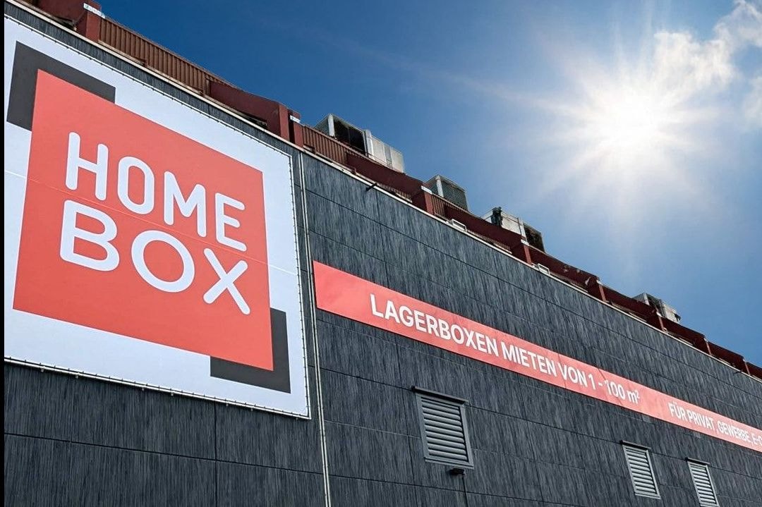 Grey facade with large HOMEBOX logo and red banner under sunny sky at HOMEBOX Essen, Schederhofstr. 59, Essen