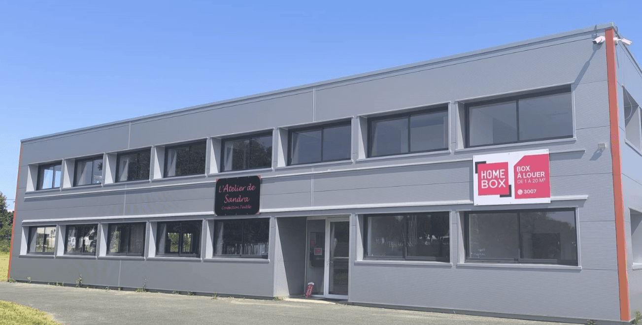 Two-storey grey building with windows and red HOMEBOX rental sign under blue sky at HOMEBOX Fontenay-le-Comte, 3 Allée du Puits, Fontenay-le-comte