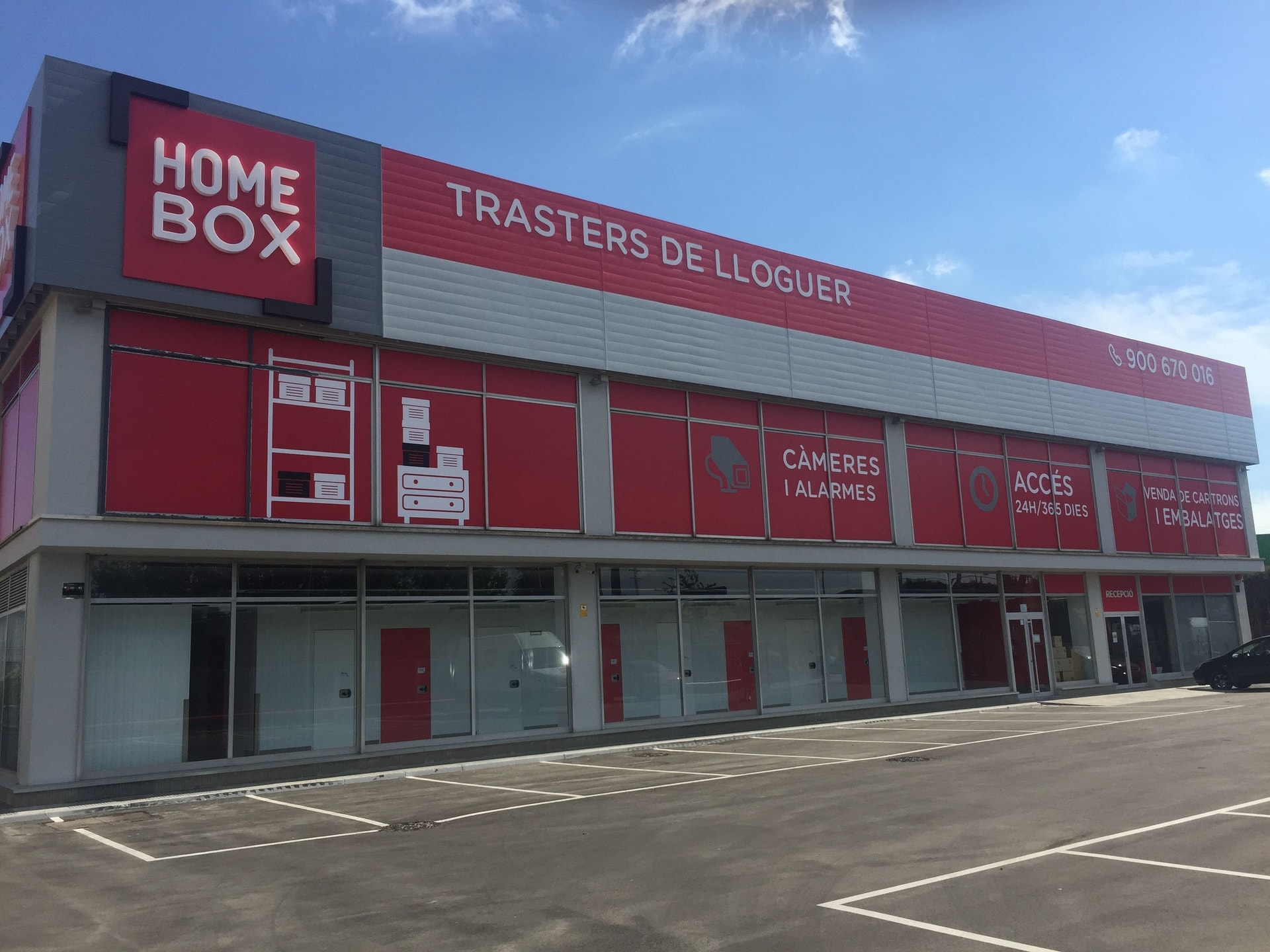 Red two-storey facade with Trasters de Lloguer signage above parking spaces at HOMEBOX Barcelona El Prat, Carretera Ca l'Alaio, 5 0 El Prat de Llobregat Barcelona, El Prat de Llobregat