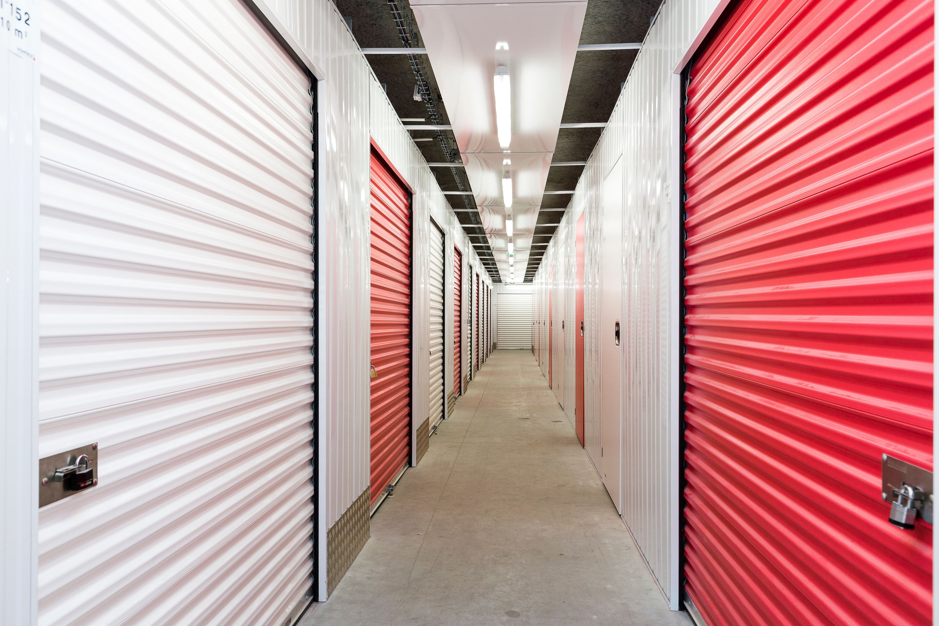 Bright corridor lined with red and white storage unit doors under fluorescent lighting at HOMEBOX Braga