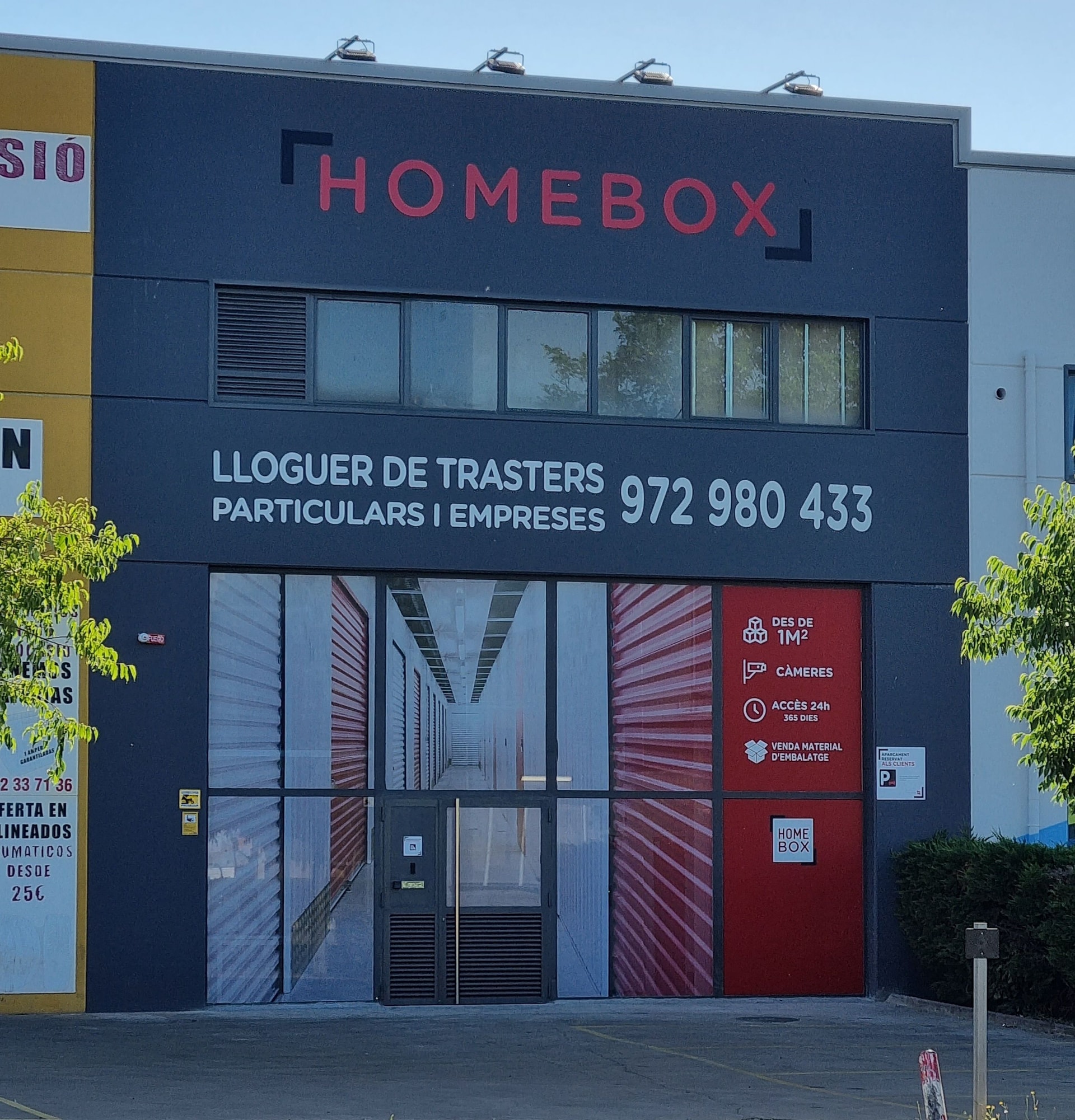 Dark grey facade with red logo and glazed entrance showing storage units at HOMEBOX Blanes, Avinguda d'Europa 26 Blanes Girona, Blanes